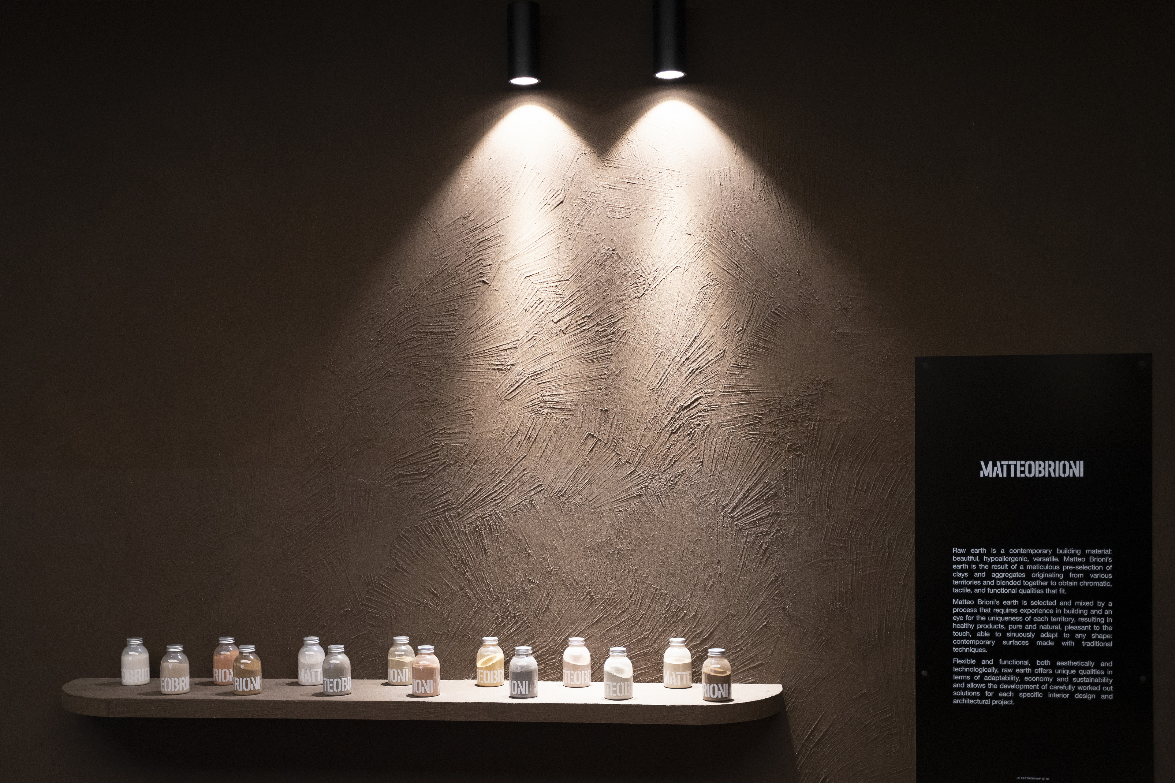 Reinforced coarse-grained clay finishing plaster MultiTerra Plus Smooth in Wengè customized color applied on panels, desk and shelves of the of the GIOPAGANI stand at the Milan Furniture Fair 2022. Photo courtedy of GIOPAGANI