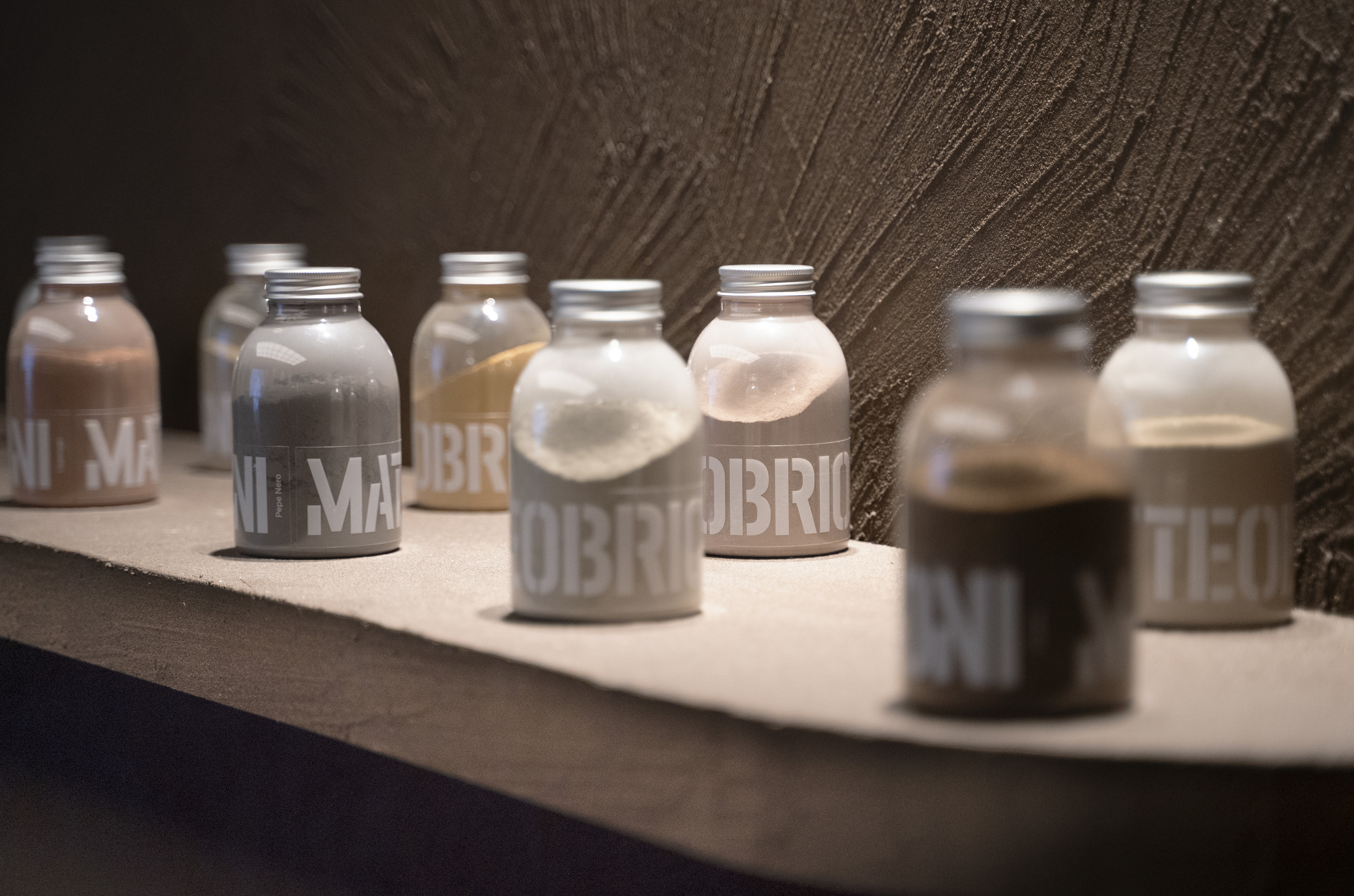 Intonaco rinforzato di finitura in terra cruda a grana grossa MultiTerra Plus Liscio in colore personalizzato Wengè, applicato su pannelli, scrivania e mensole dello stand GIOPAGANI al Salone del Mobile di Milano 2022. Foto per gentile concessione di GIOPAGANI