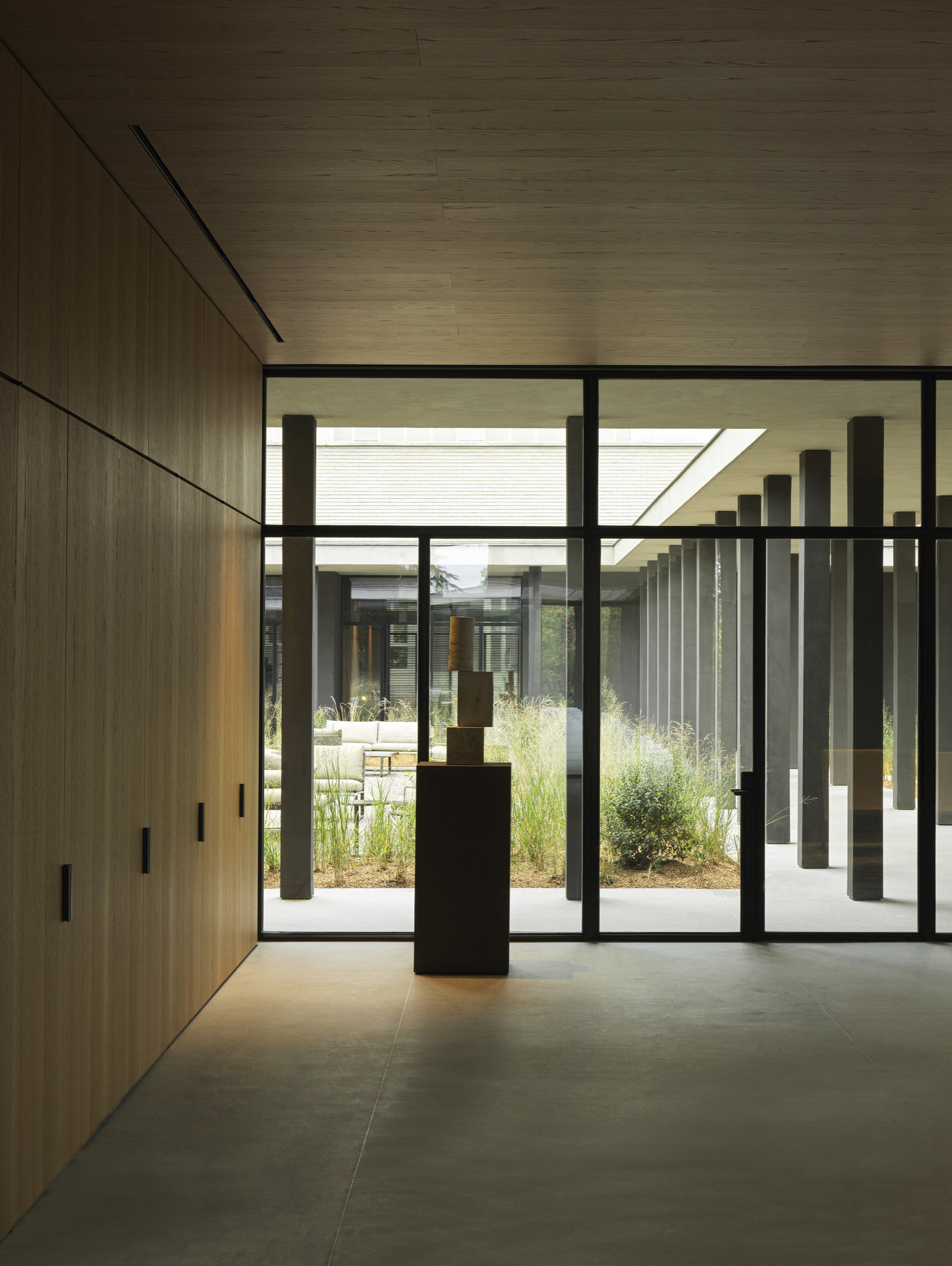 TerraTon Wall Smooth Pepe Nero and Polvere finishing plaster based on natural pozzolans clay, cement and fine-grained mineral binders applied to pillars and walls in the exteriors while TerraVista Smooth Panna, Cacao and Polvere fine-grained clay finishing plaster for the interiors of the Molteni's headquarters expansion in Giussano. Project by Vincent Van Duysen. Photography: DSL Studio-Delfino Sisto Legnani